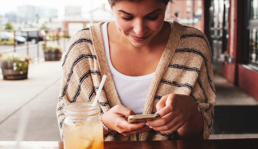 A woman looking at her phone while sitting at a table.