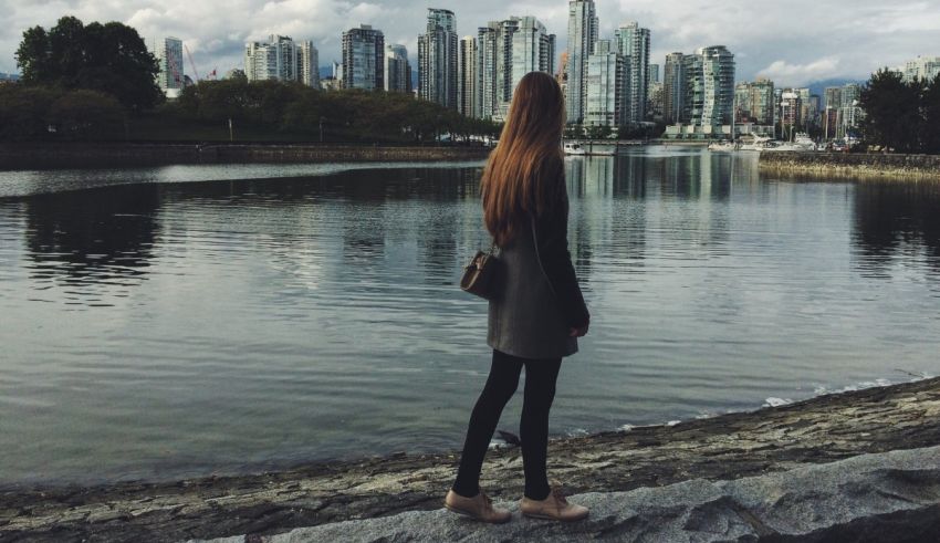 A woman is standing on a rock next to a body of water.