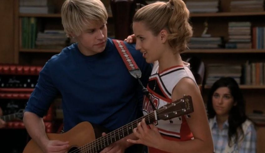 A man and a woman standing next to each other playing an acoustic guitar.