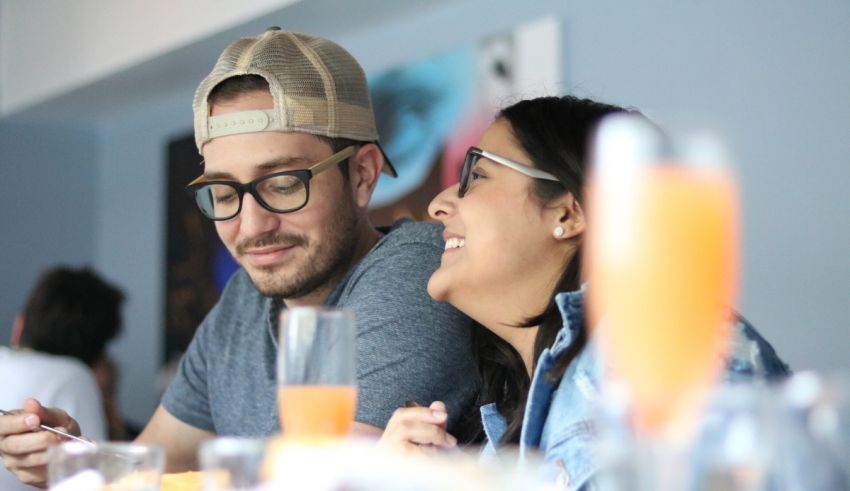 A man and woman sitting at a table looking at their phones.