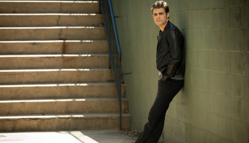 A young man leaning against a set of stairs.