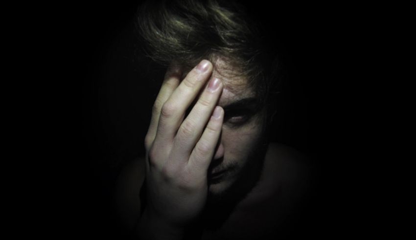 A man covering his face with his hands in the dark.