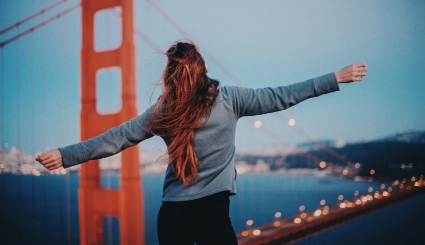 A woman standing on the golden gate bridge with her arms outstretched.