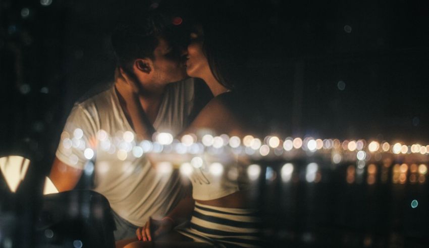 A man and woman kissing in front of candles.