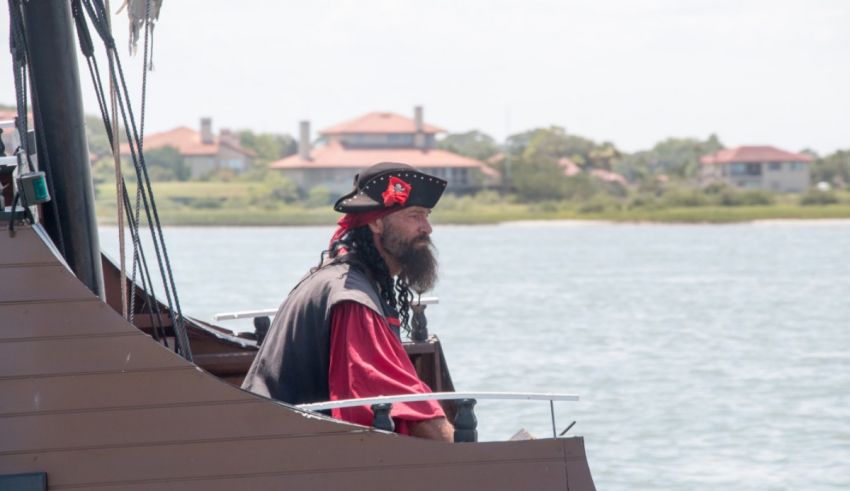 A man dressed as a pirate is standing on the deck of a boat.
