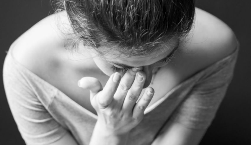 A black and white photo of a woman covering her face.