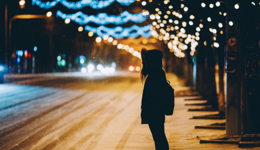 A woman standing on a snowy street at night.