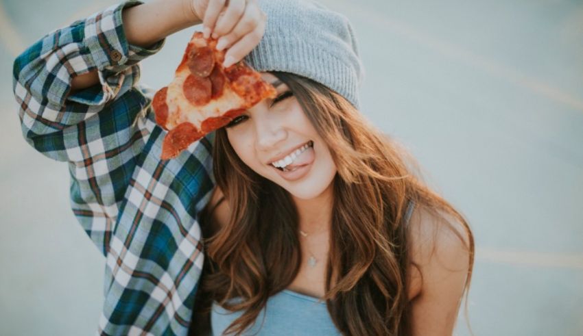 A young woman holding a slice of pizza.