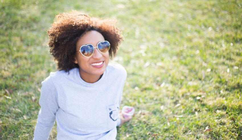 A woman wearing sunglasses sitting on the grass.