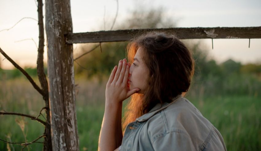 A woman is holding her hand over a fence in a field.