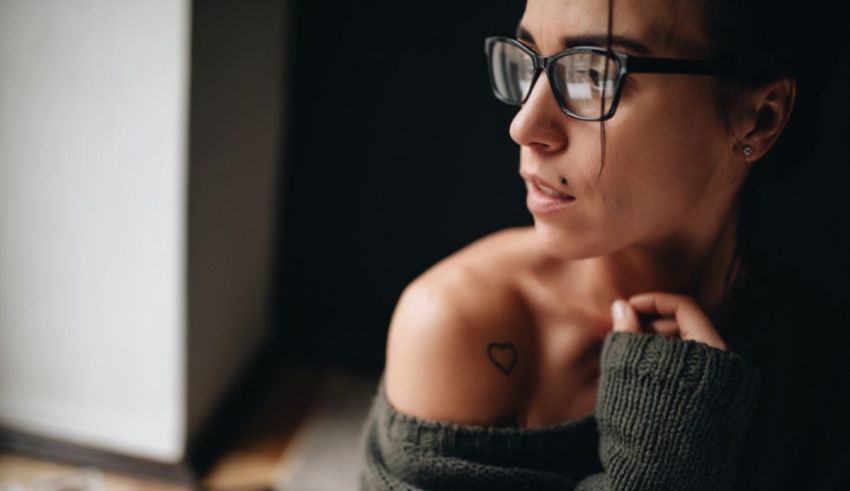 A woman wearing glasses and a tattoo on her arm.