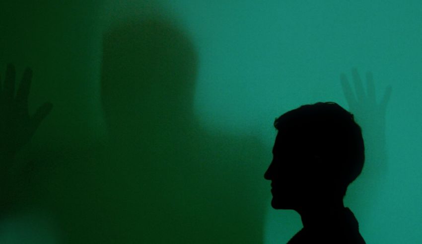 A silhouette of a man in front of a green wall.