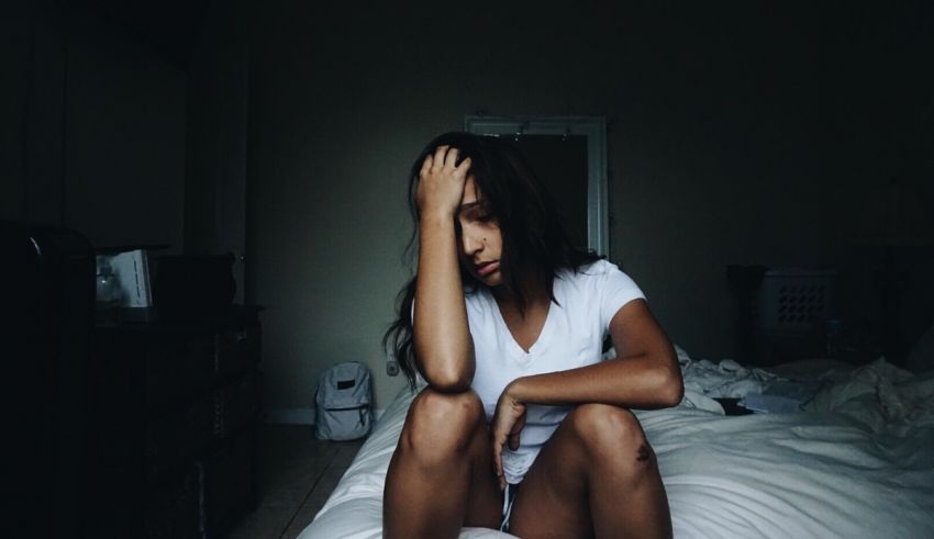 A woman sitting on a bed in a dark room.