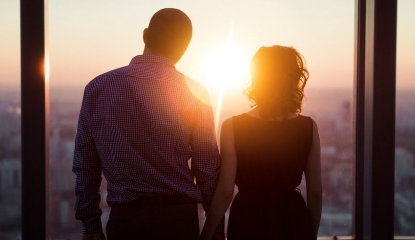 A man and woman are standing in front of a window overlooking a city.