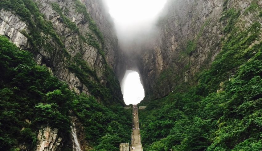 A bridge leading to a waterfall in the middle of a mountain.