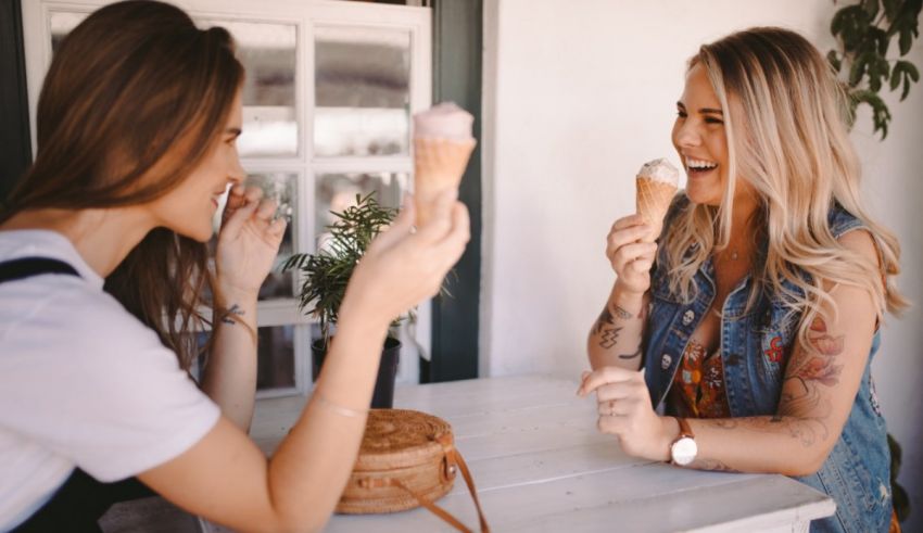 Two women eating ice cream cones at a table.