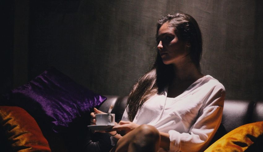 A woman sitting on a couch holding a cup and saucer.