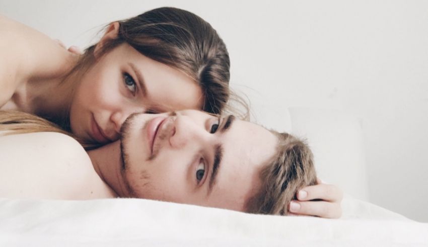 A young man and woman laying on a bed.