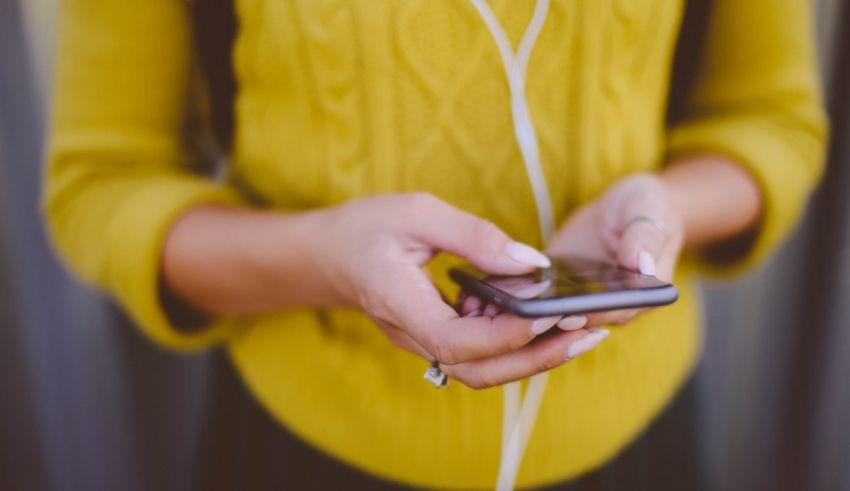 A woman holding a cell phone and listening to music.