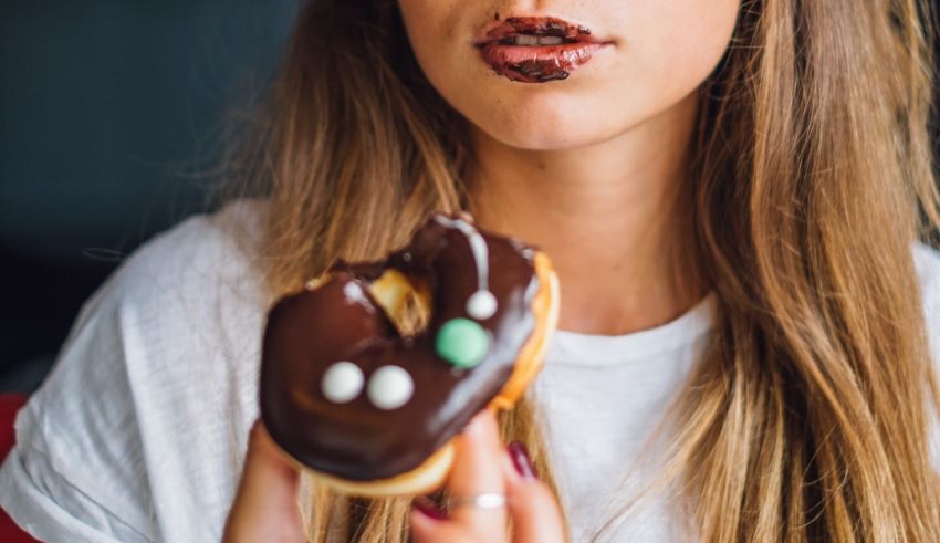 A woman is eating a chocolate donut.
