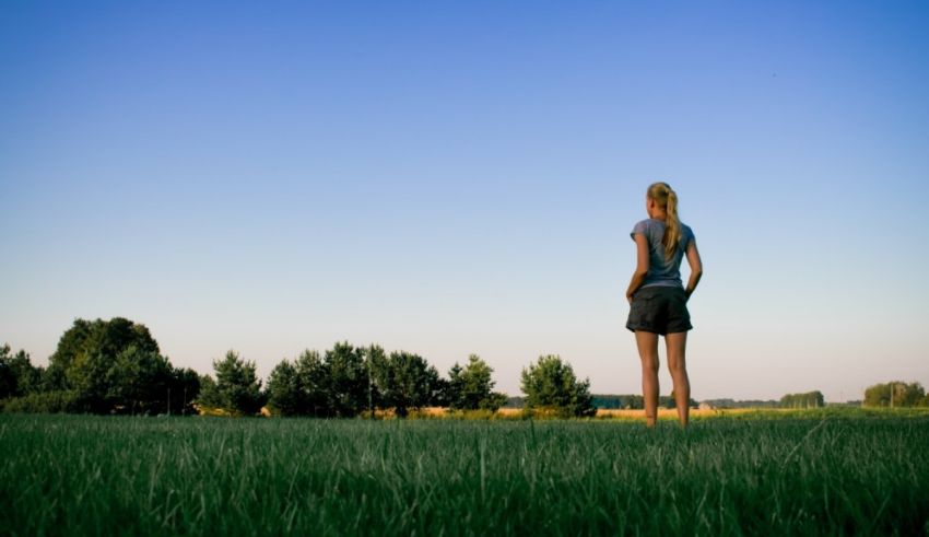 A woman standing in a field looking at the sky.