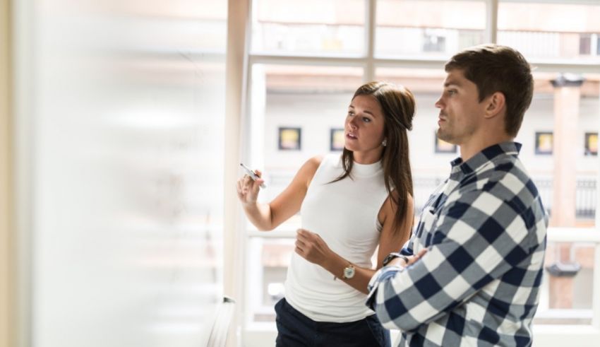 Two people standing in front of a whiteboard.