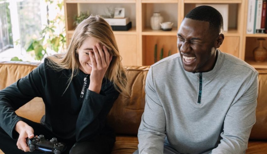 A man and woman sitting on a couch playing video games.