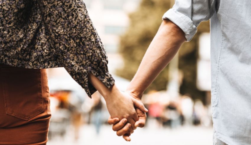 A man and woman holding hands on a city street.