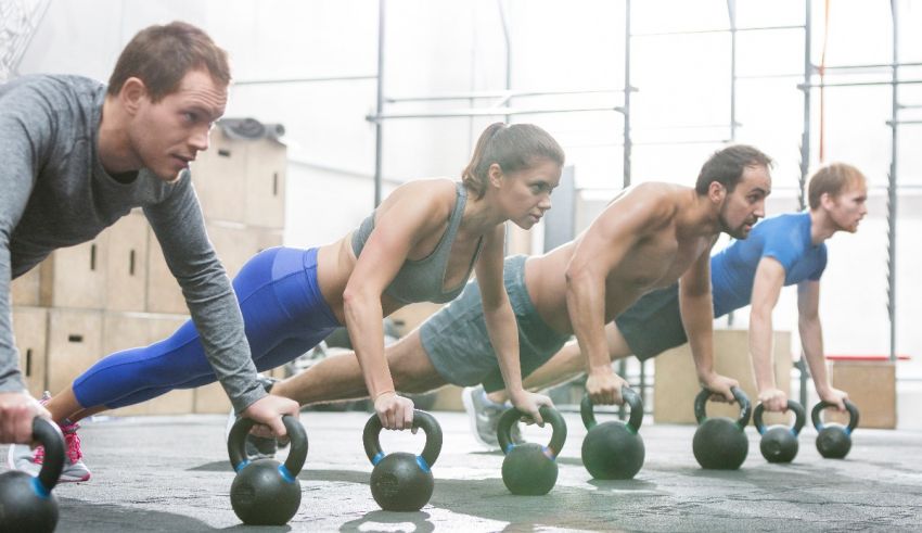 A group of people doing kettlebell exercises in a gym.