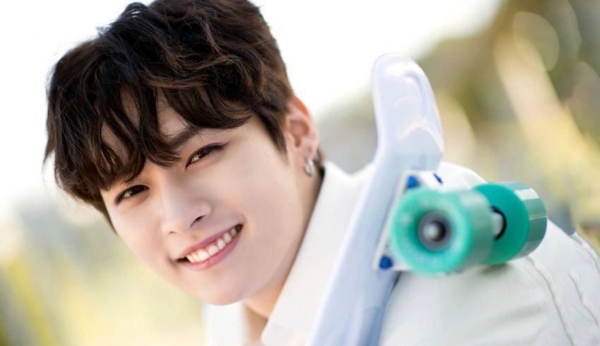 A young man is smiling while holding a skateboard.