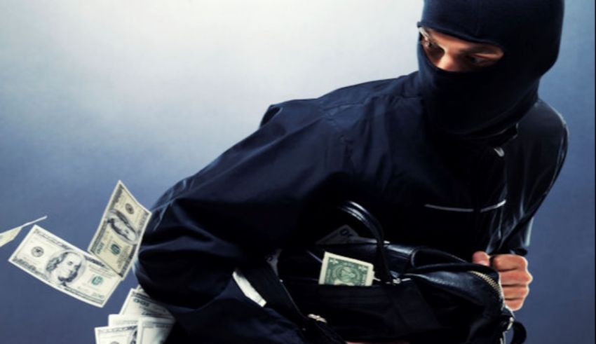 A man in a black mask holding money.