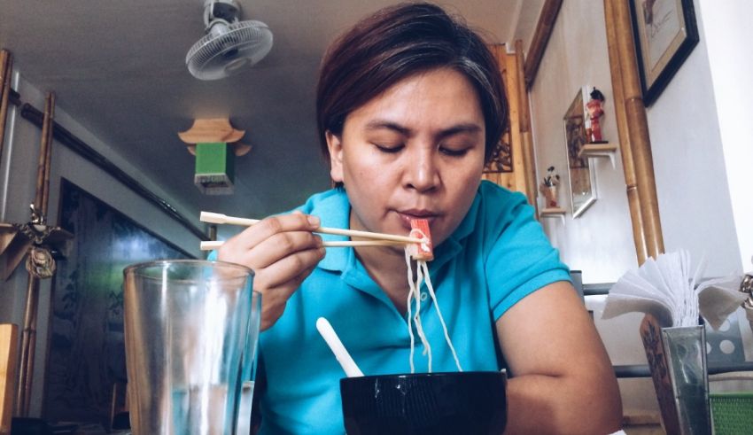 A woman eating noodles with chopsticks.