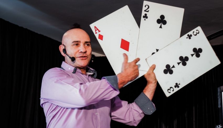 A bald man holding up a deck of playing cards.