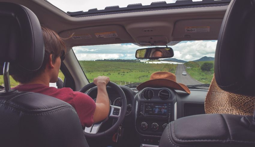 Two people driving a car in the countryside.