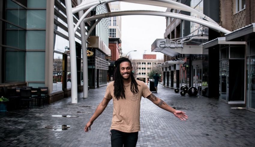 A man with long dreadlocks standing on a sidewalk.