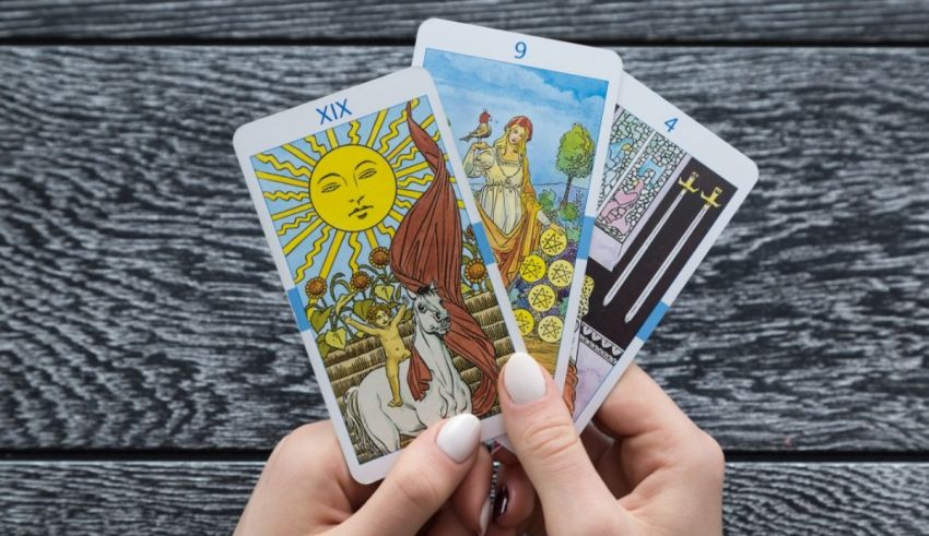 A woman holding tarot cards on a wooden background.