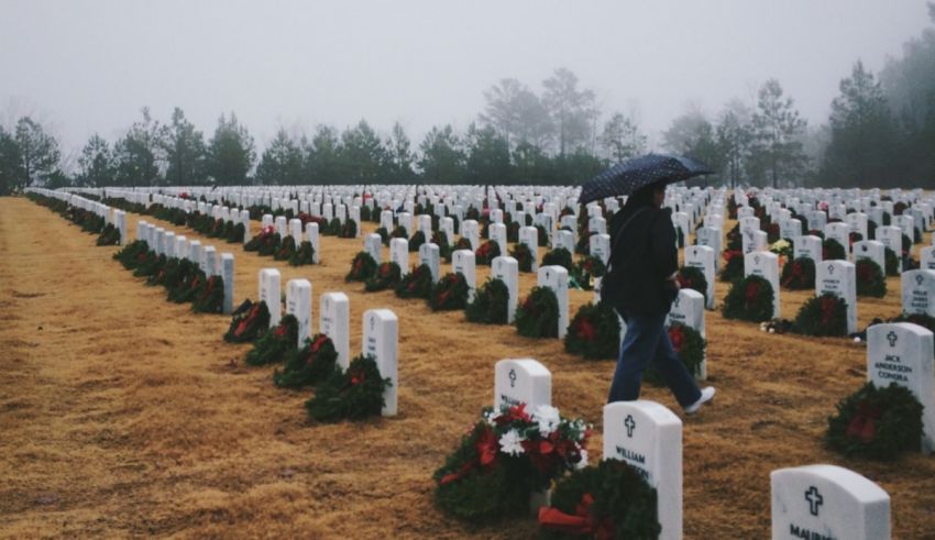 A person walking through a cemetery with wreaths.