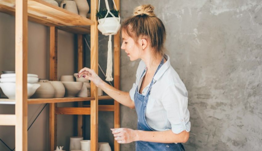 A woman in overalls is working in a pottery studio.