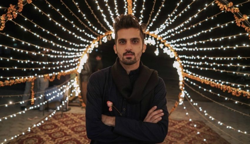 A man standing in front of a string of lights.
