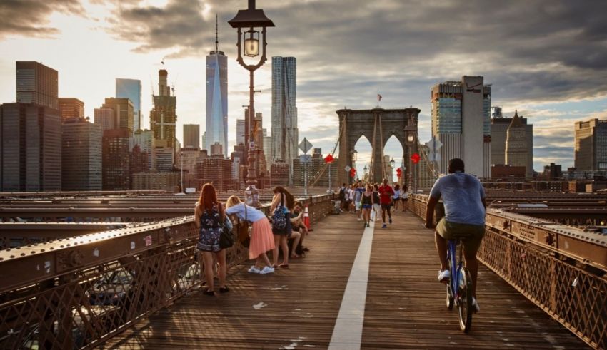 People walking on the brooklyn bridge at sunset.