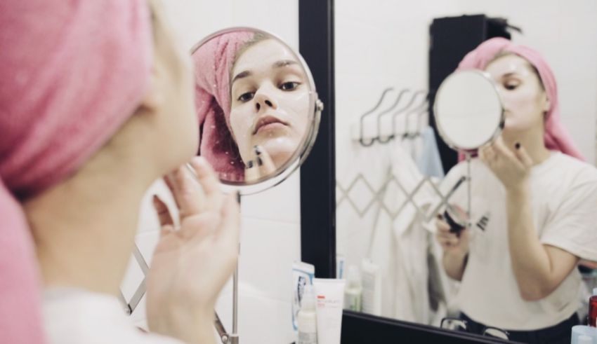 A woman is putting on makeup in front of a mirror.