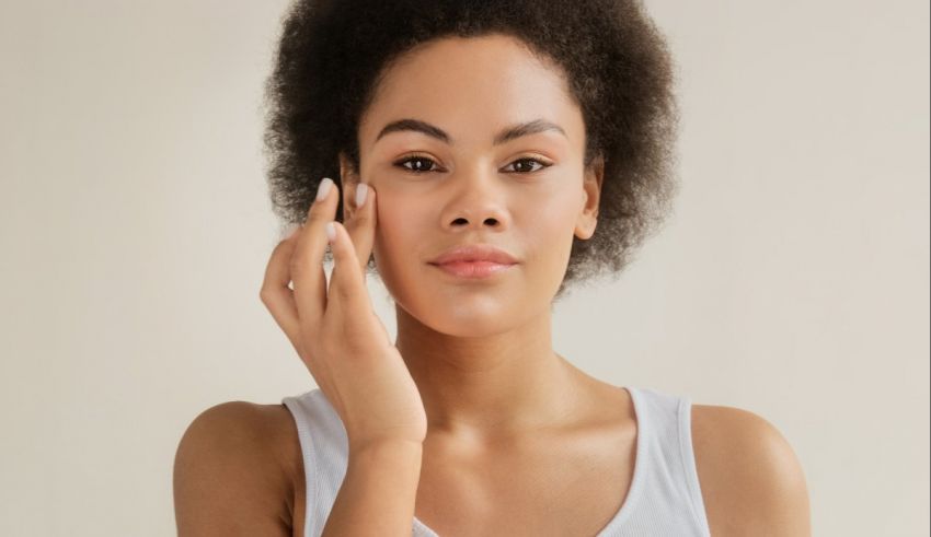 A young woman with afro hair putting cream on her face.