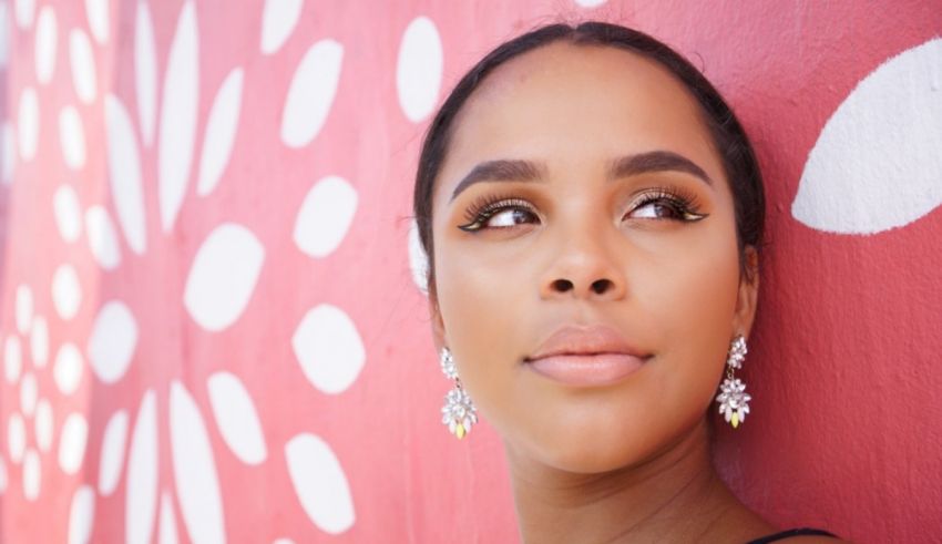 A black woman leaning against a pink wall.