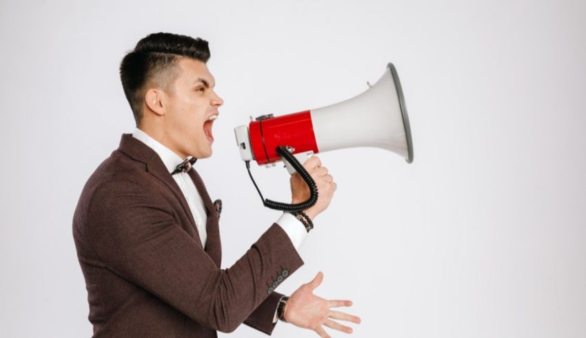 A man in a suit yelling into a megaphone.