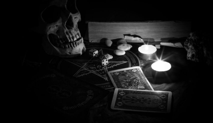 A black and white photo of a skull with a pentacle and playing cards.