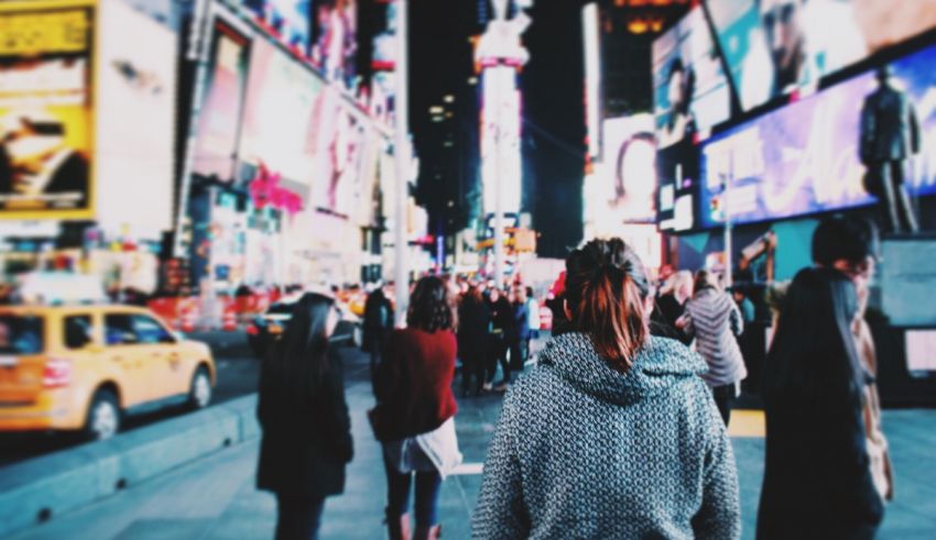 A woman walking down the street in times square at night.