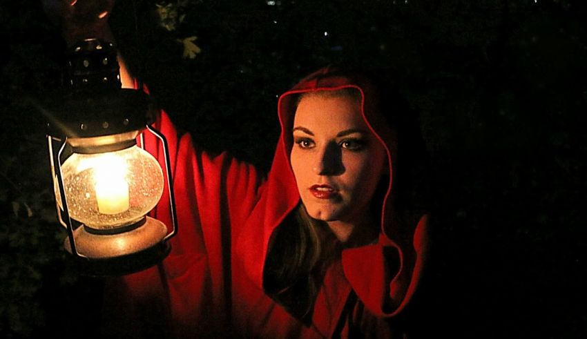A woman in a red cloak holding a lantern.