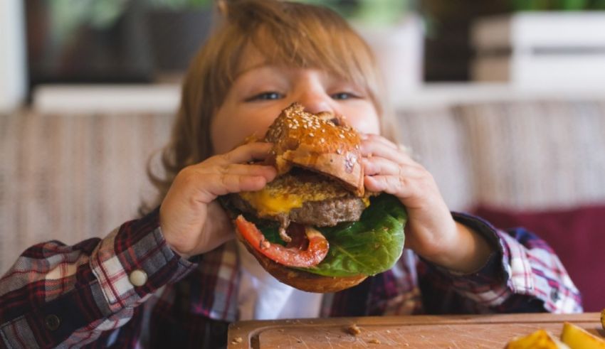 A young boy is eating a hamburger with fries.