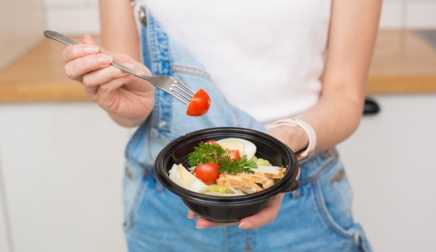 A woman holding a bowl of salad with a fork.