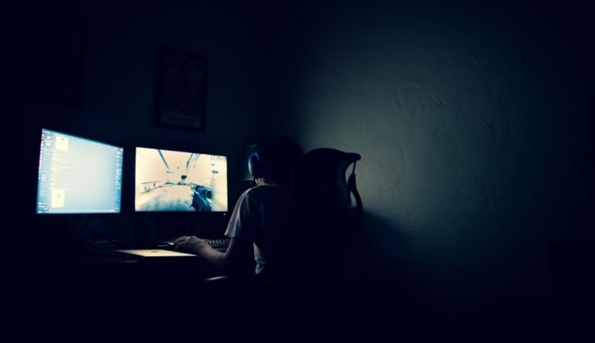A person sitting at a computer in a dark room.